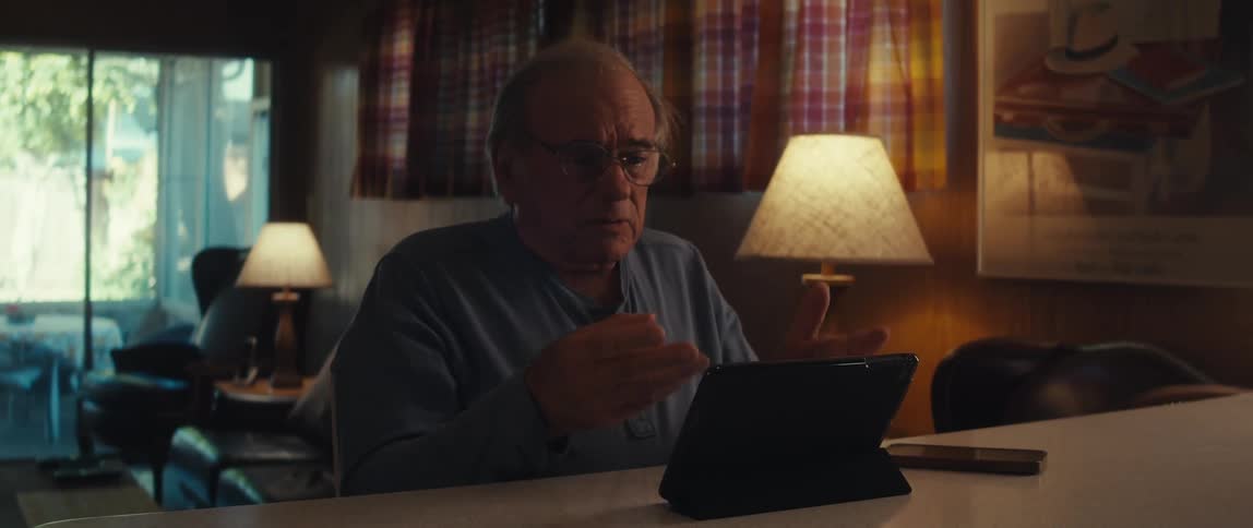 Elderly man sitting interacting and talking in front of a tablet