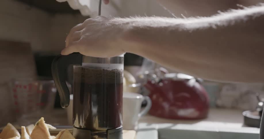 A man presses coffee grounds in french press