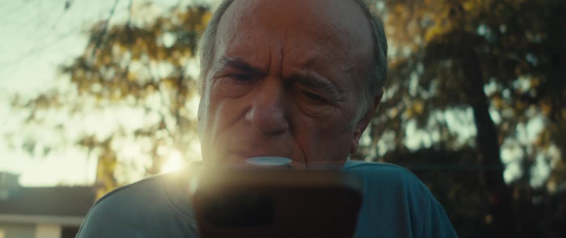 The face of an elderly man using a cell phone in an outdoor environment