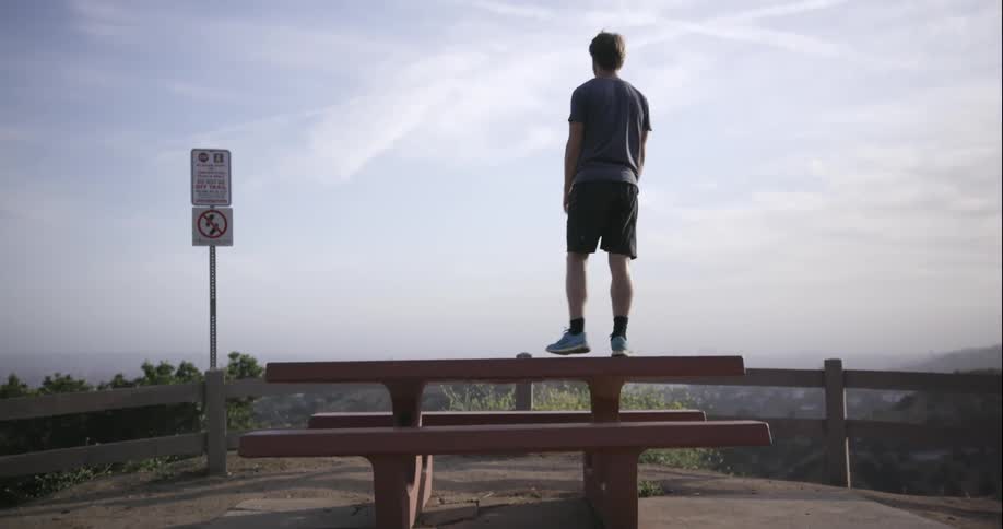 A man hopes on top of a picnic table