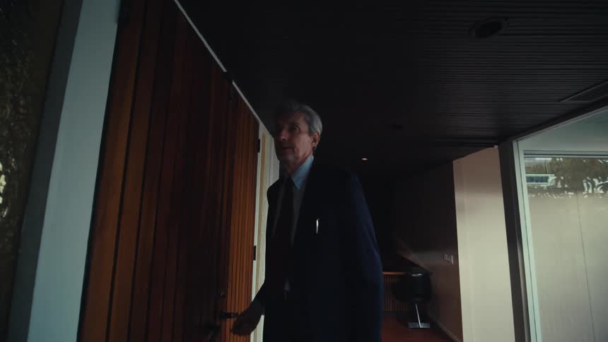 Man in suit entering house and leaving his briefcase
