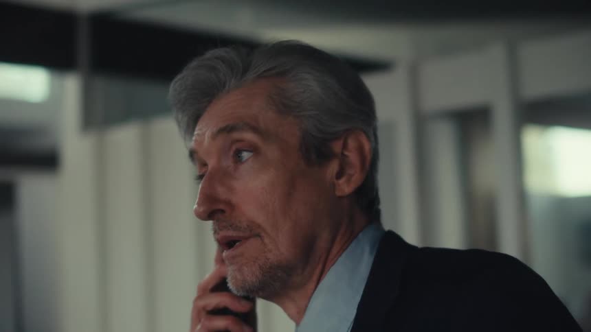 Businessman wearing a suit talks on the phone at the office
