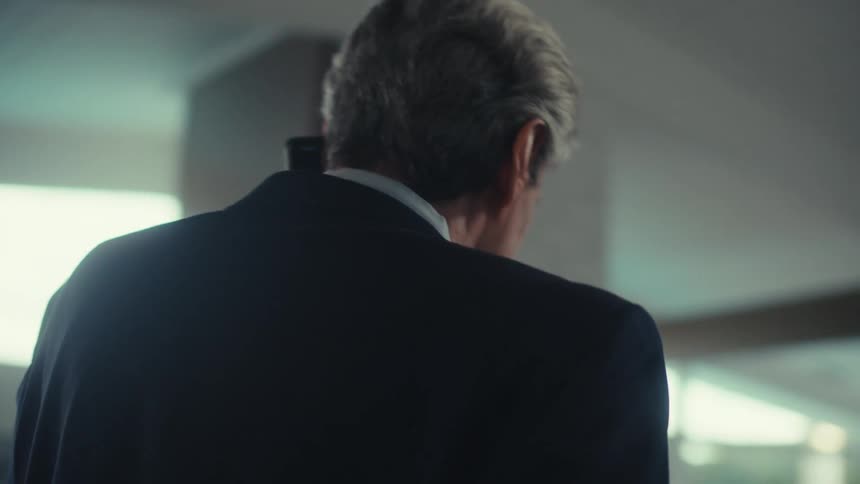 The businessman wearing a suit paces the office talking on his smartphone