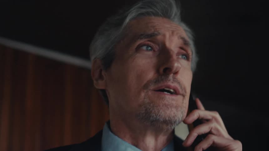 Businessman wearing a suit talks on the phone at the office