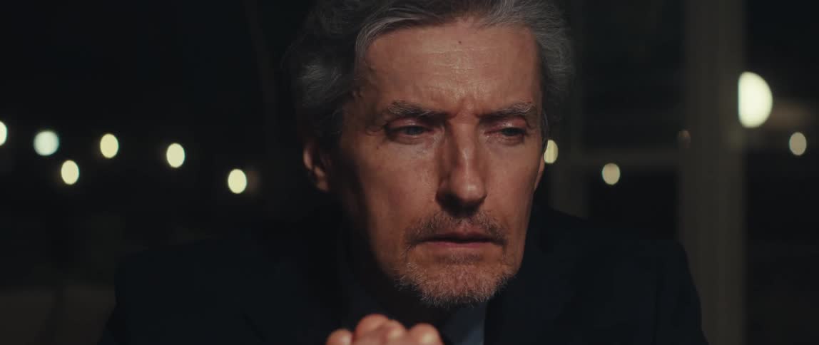 Closeup of a tired mans face as he reads something late at night