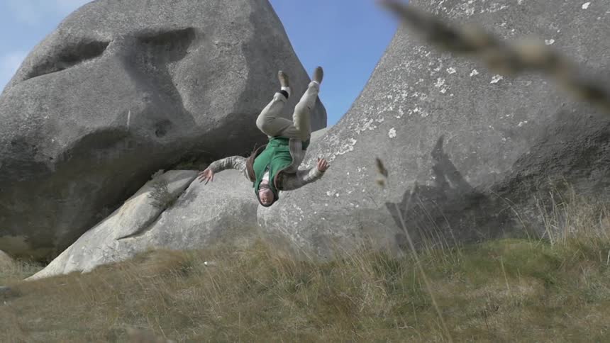 A man launches off of a boulder and does a backflip