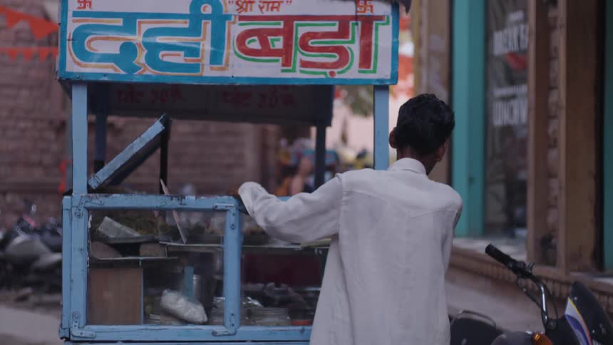 Man walking through the streets of a city carrying his food truck on foot