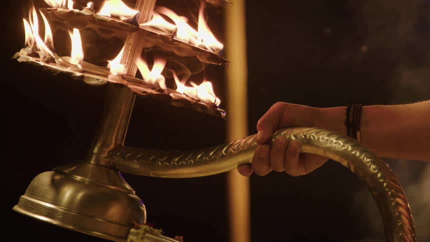 Hand holding a bronze chalice with flames of fire at a festival