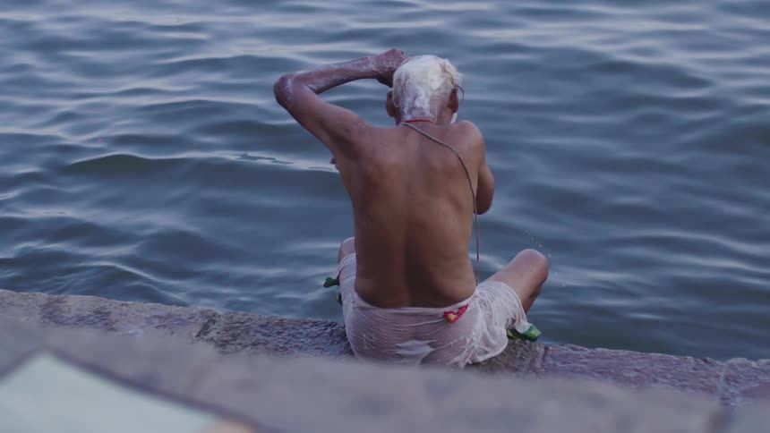 Elderly man sitting bathing in the river
