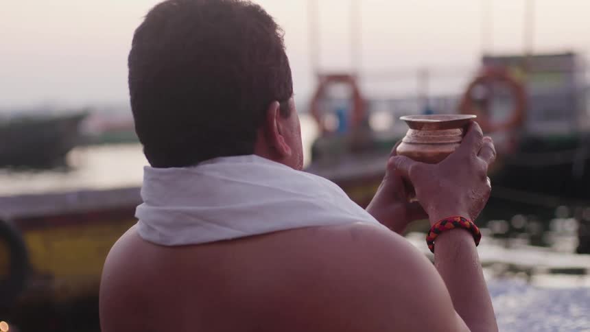 A man is holding up a container full of water at the harbor