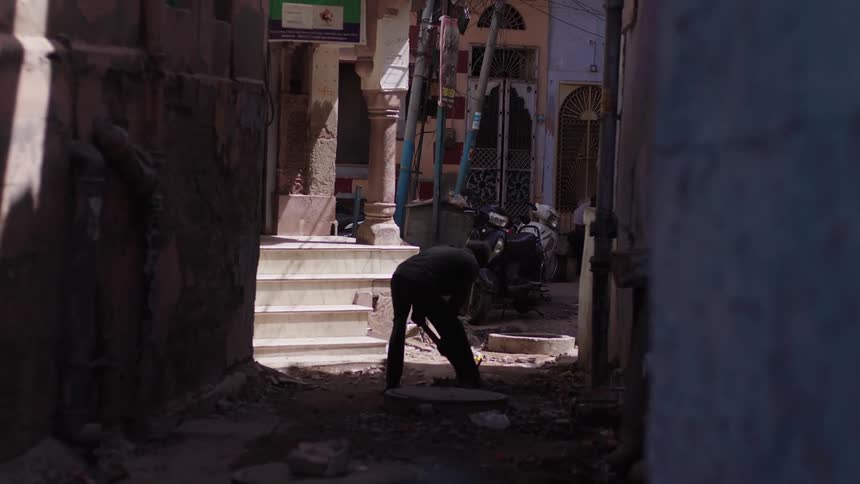 Man with a pickaxe working in an alley between houses