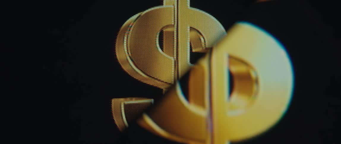 Close up of a shimmering dollar sign bisected by a diagonal line creating a distorted and fragmented reflection