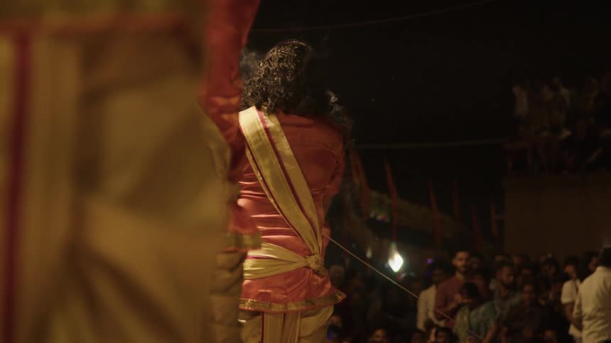 People in costume performing with incense and a crowd of people watching