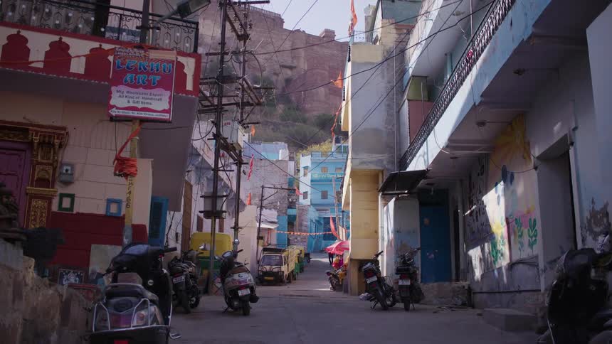 Narrow street surrounded by classic buildings with parked vehicles