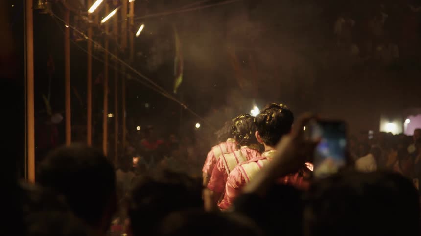 Crowd of people watching a performance of people holding chalices with fire