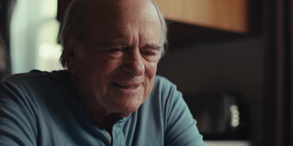 Elderly man sitting happily interacting with an iphone