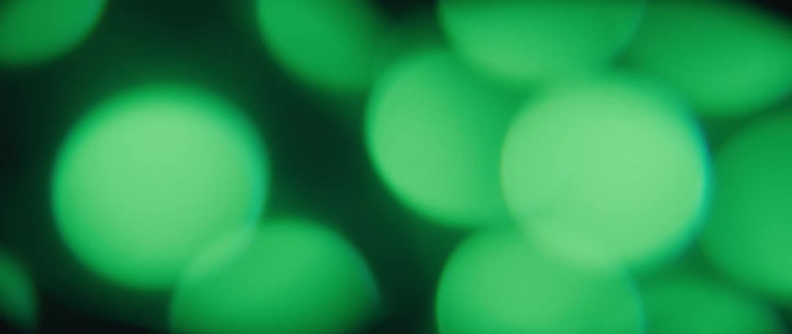 An abstract shot of outoffocus green lights appearing as floating orbs moving up and down while turning on and off