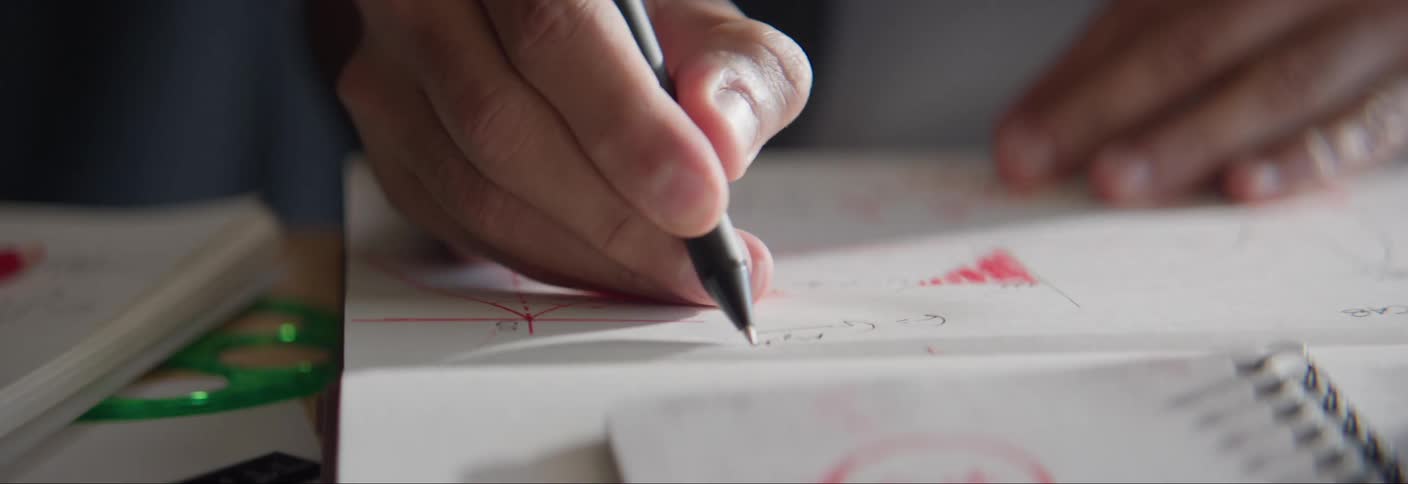 A persons hand using a black pen to write on a white paper