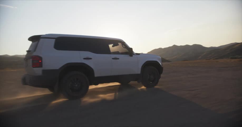A white suv drives through a desert landscape kicking up dust and showcasing its offroad capabilities against a backdrop of distant mountains