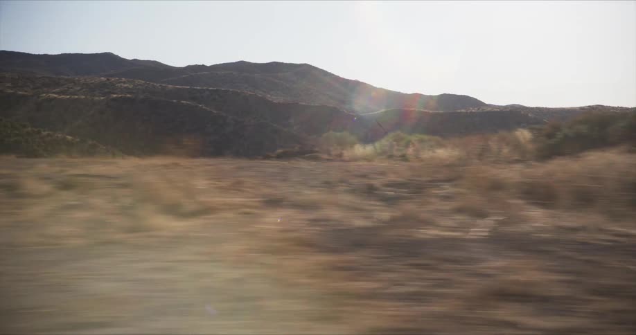 A white suv speeds through a desert landscape kicking up dust and leaving a trail behind as it navigates the rugged terrain
