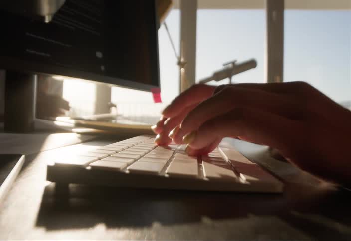 Hands of a woman typing on a computer keyboard