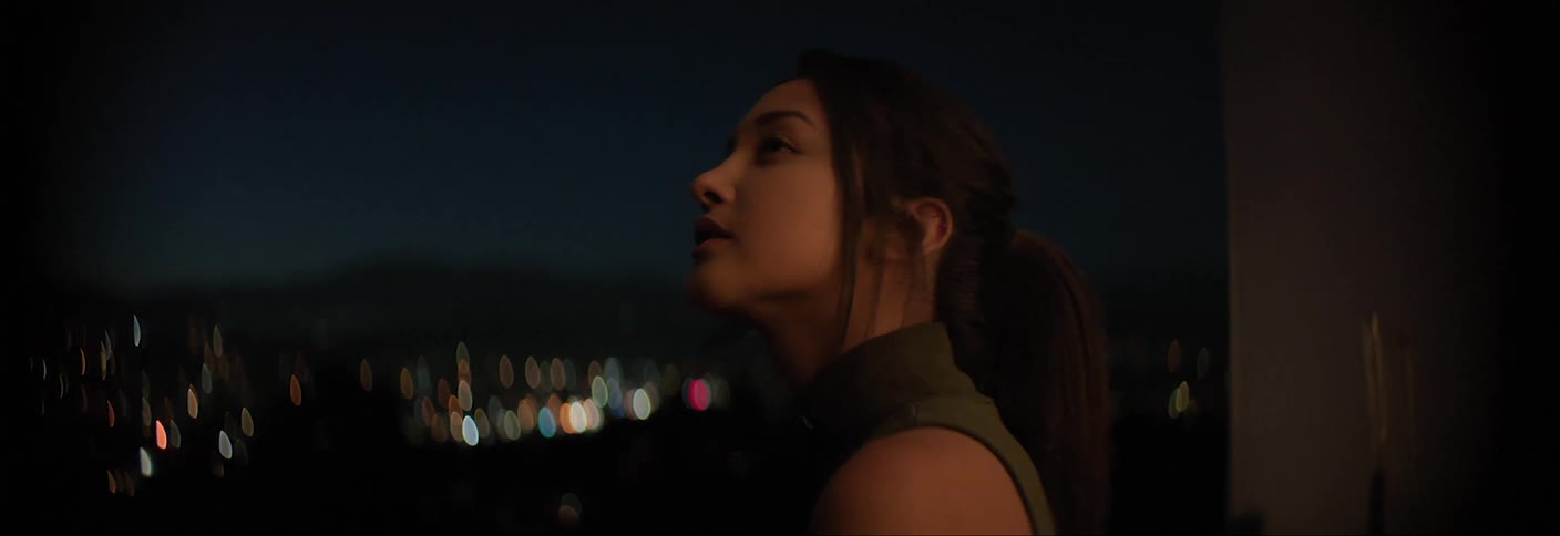 Female standing by a window and looking at the city skyline at night
