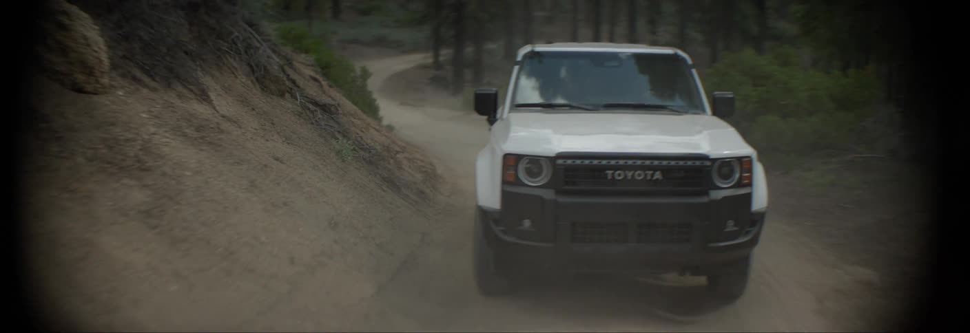 A white toyota suv navigates a challenging offroad course kicking up dust as it conquers the terrain