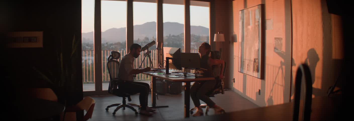 Woman walking into an office room and sitting down in front of the computer
