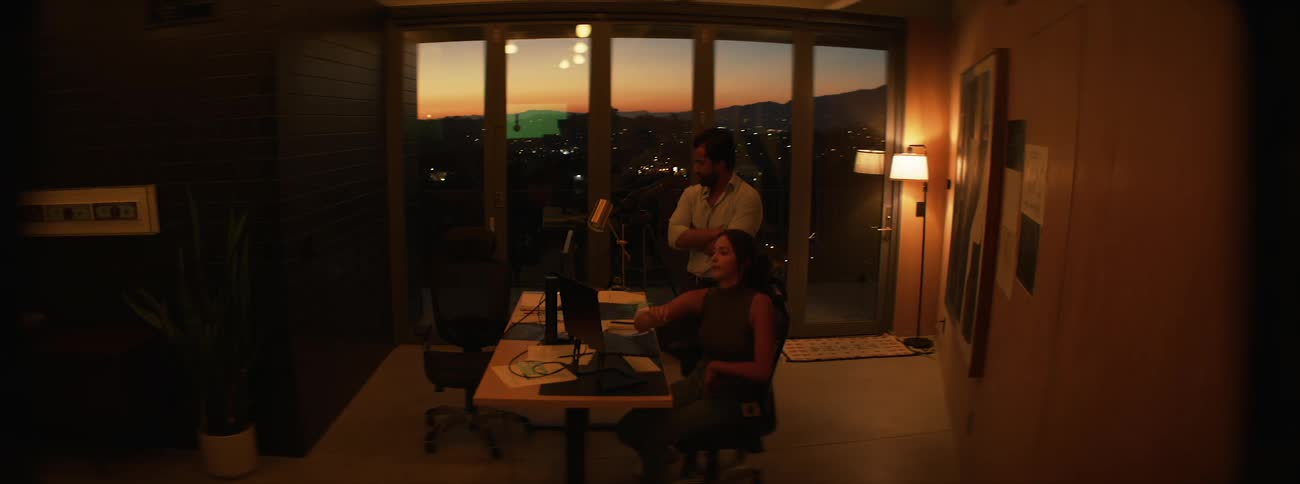 Man getting up from his desk and walking to a womans side in an office setting