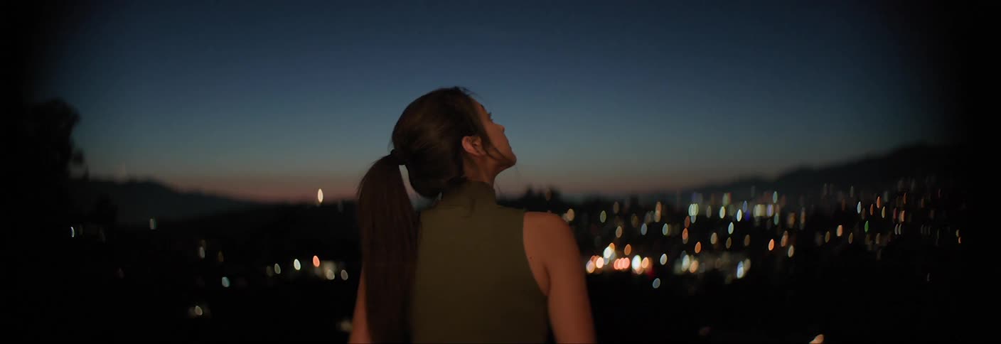 Woman outdoors with panoramic view of a city at night