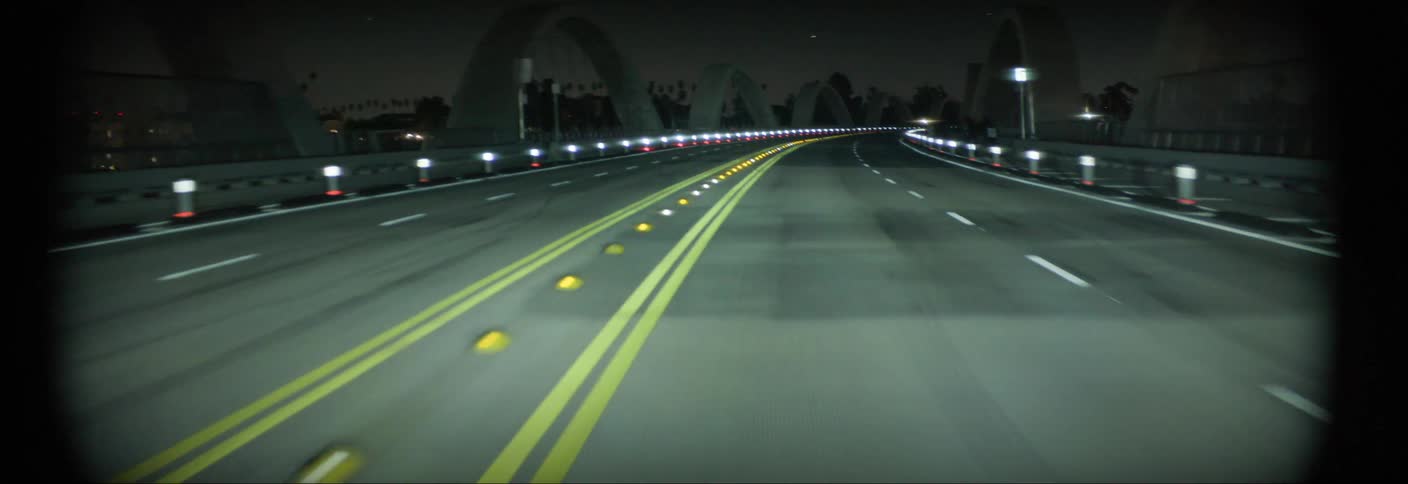 Moving view of an overpass illuminated by vehicle headlights at night