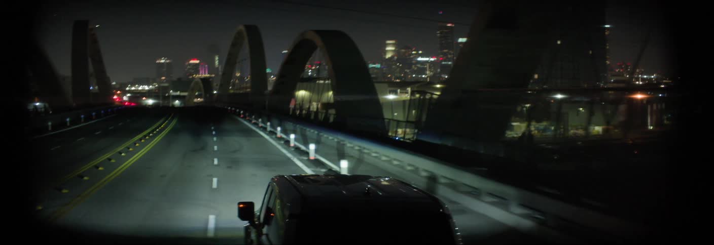 Car traveling across a bridge in a metropolis at night