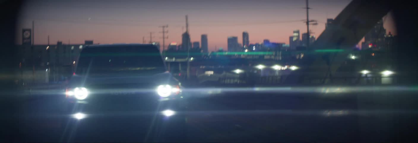 Toyota car with headlights on traveling on a city highway at night