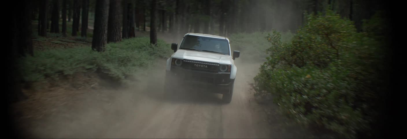 A white toyota suv drives down a dirt road in an evergreen forest