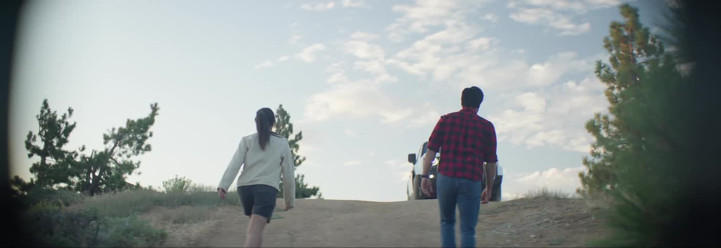 Man and woman walking up a hill towards a pickup truck
