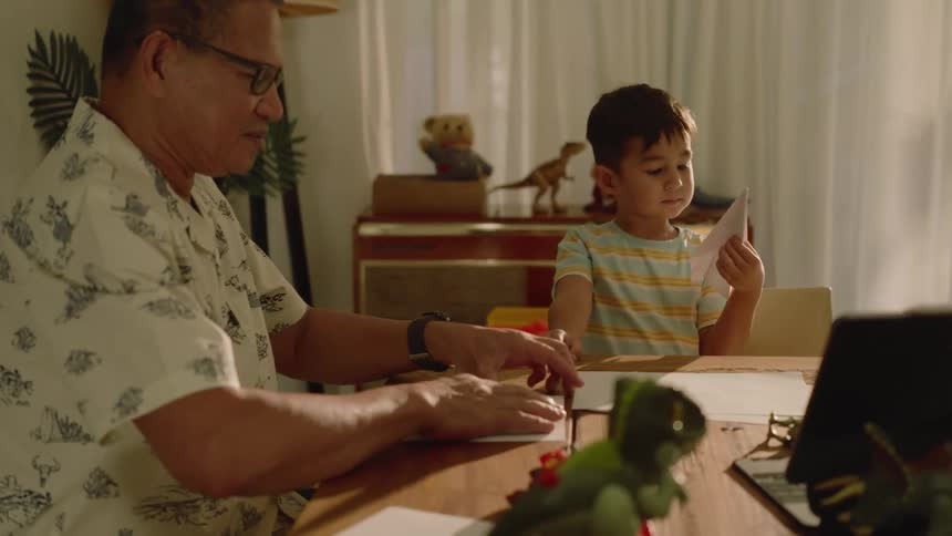 A clip of a grandfather making a paper plane for a kid