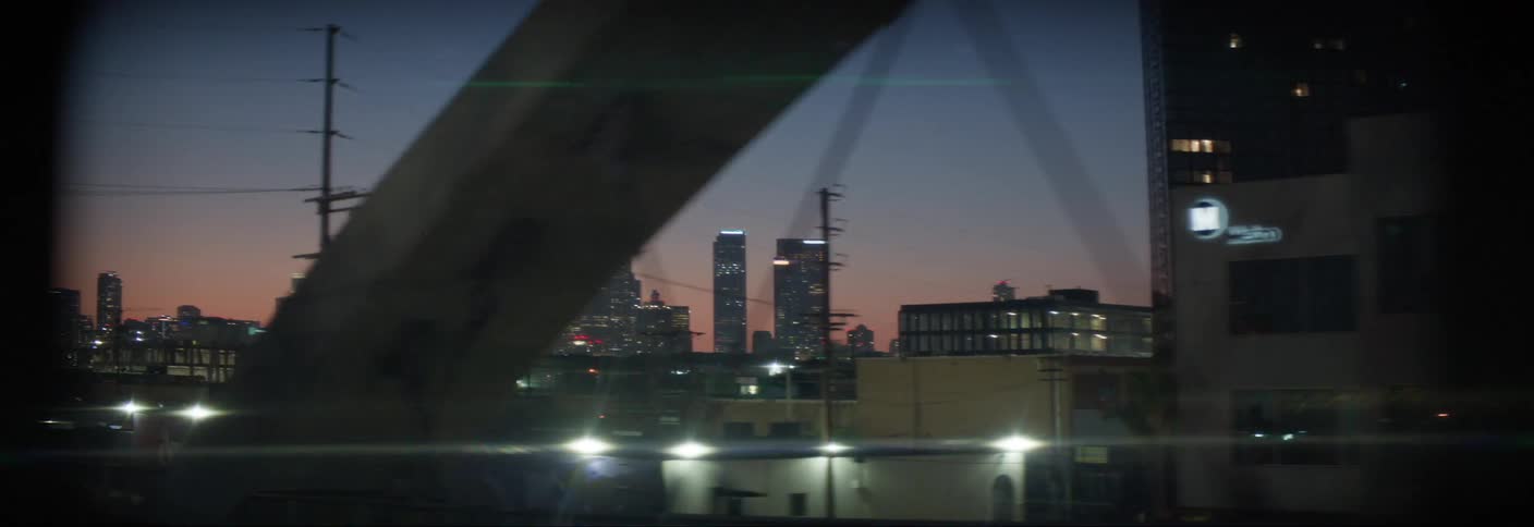 A distant city center with several tall buildings and lights on at dusk