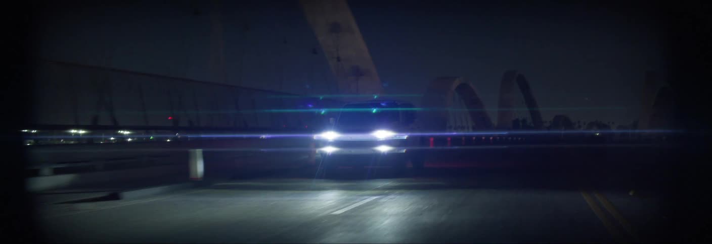 Vehicle traveling across a bridge in the city at night