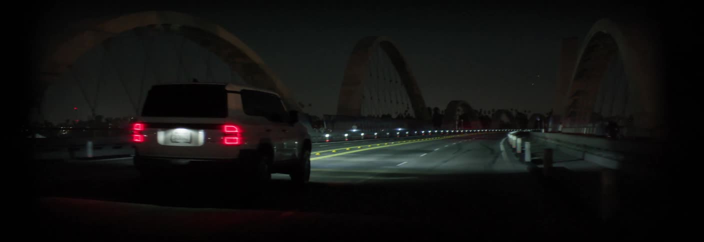 White vehicle passing over a bridge in the city at night