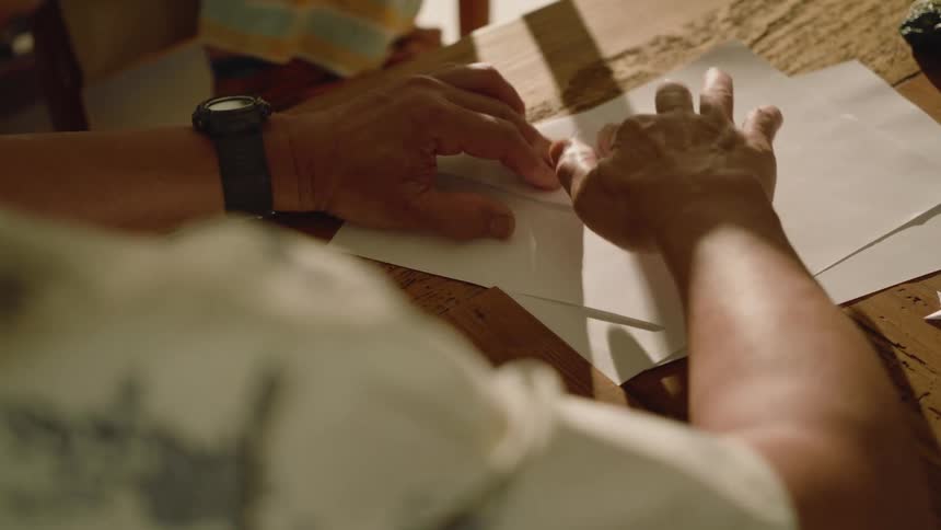 A man is showing a child how to make a paper airplane