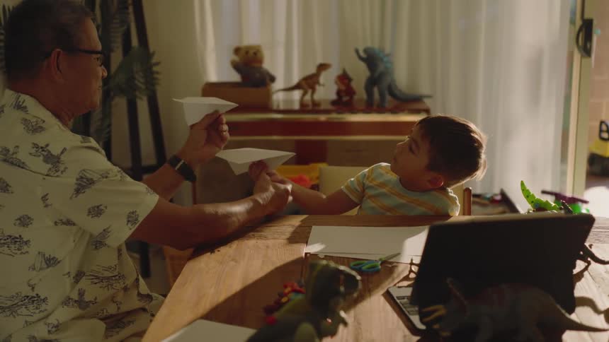 Grandma teaching her grandson to play with a paper airplane