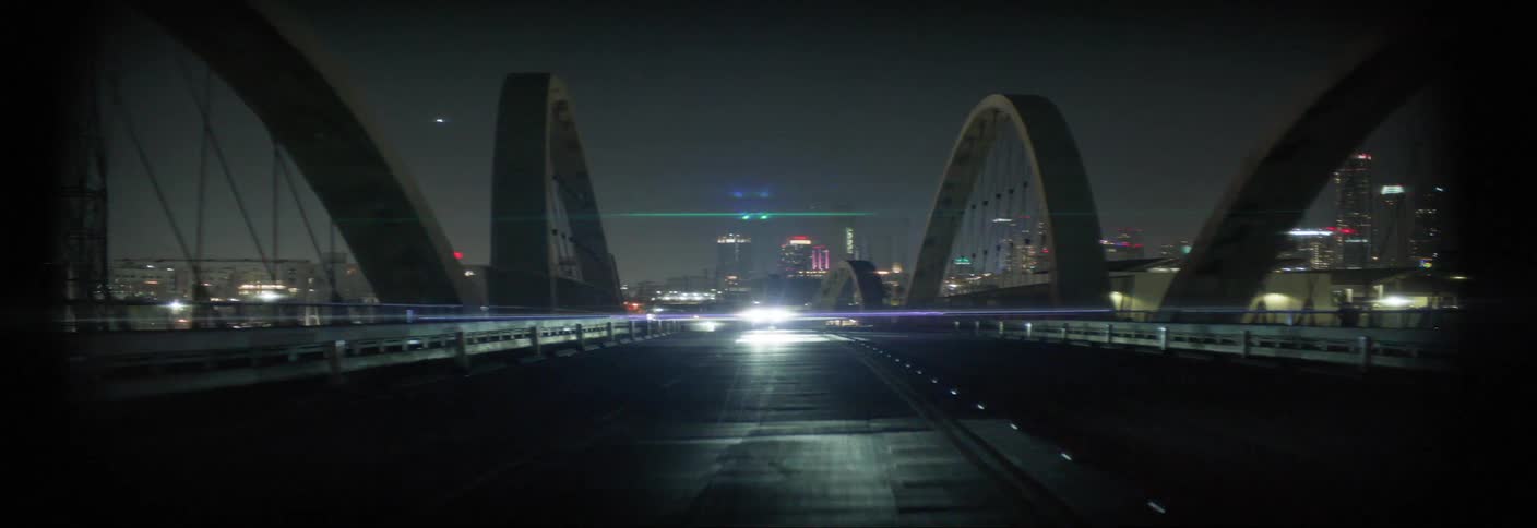 Bridge illuminated at night with striking structural arches and a car with headlights on