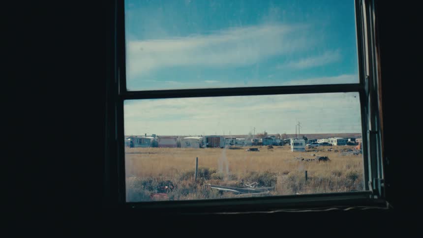View from a window to a field with houses in the background