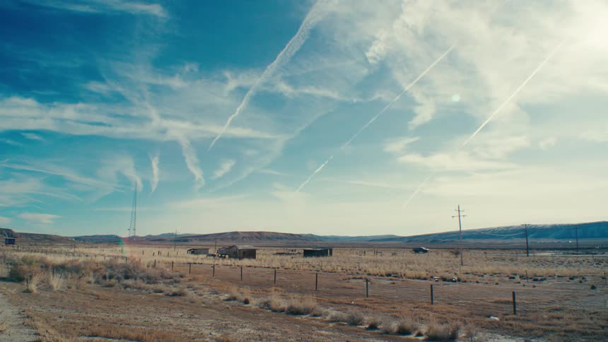 A cluster of weathered abandoned buildings stands forlorn amidst a vast barren landscape hinting at a forgotten past and the passage of time
