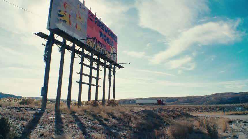 A faded billboard advertising a worlds biggest attraction stands weathered and forgotten in a desolate landscape hinting at a bygone era of roadside commerce