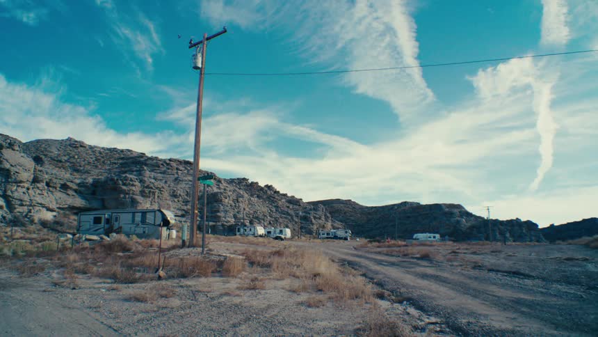 A row of weathered trailers sits nestled against a cliff face their presence hinting at a makeshift community in a remote rugged landscape