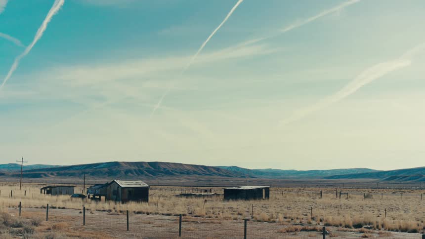 A cluster of abandoned dilapidated houses scattered across a desolate windswept landscape