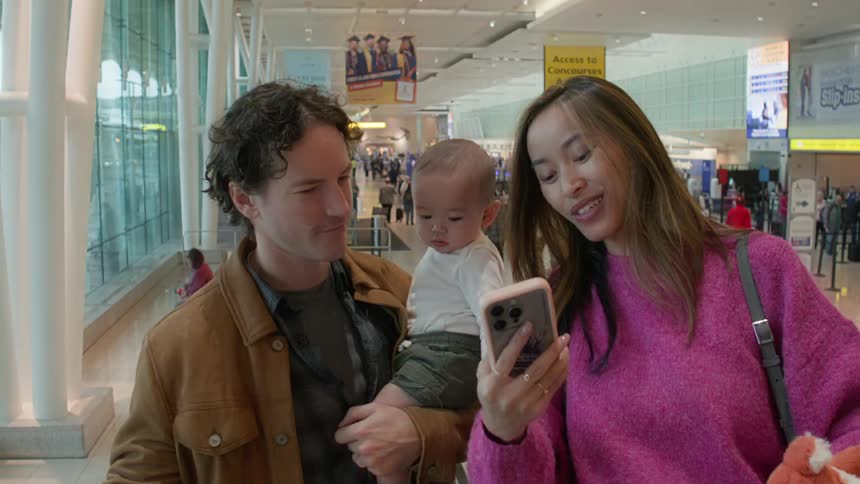 Family including a baby taking a selfie on an escalator at the airport