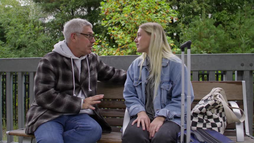 Woman and a man sitting on a bench outdoors talking