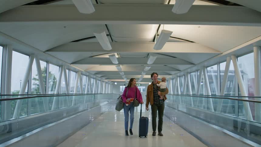 Family with a baby walking through an airport station